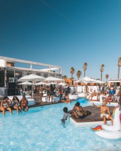 people gathered around an outdoor pool on a nice day with a Pool Party DJ