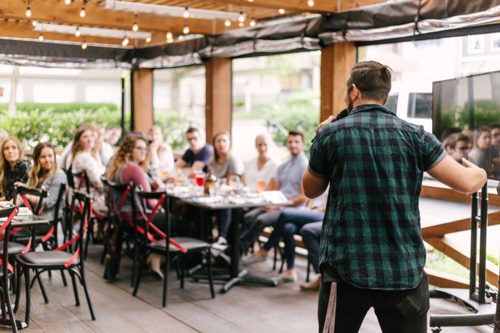 man speaking to audience at dinner party